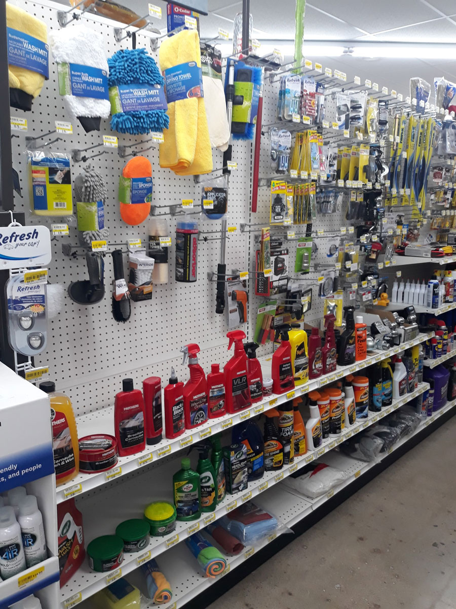 Store aisle at Carlisle Hardware with shelves displaying various car care products. Items include cleaning sprays, wax containers, microfiber cloths, and brushes, all neatly arranged. Pegboard above holds different tools and accessories.